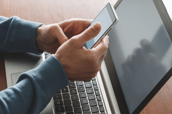 Hands holding a computer in front of a laptop computer
